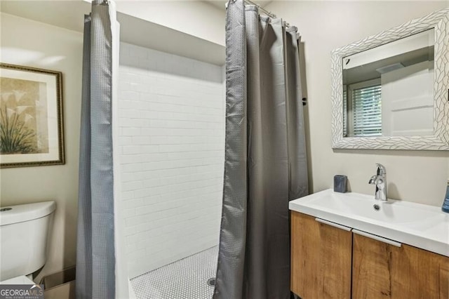 bathroom with vanity, toilet, and tiled shower