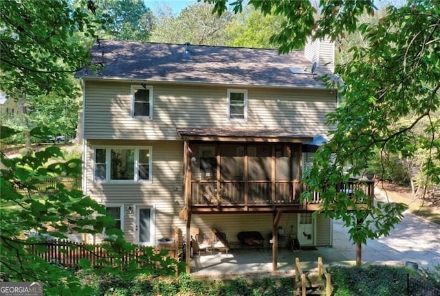 back of property featuring a chimney, fence, a patio, and a sunroom