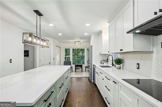 kitchen with a sink, white cabinets, under cabinet range hood, appliances with stainless steel finishes, and tasteful backsplash