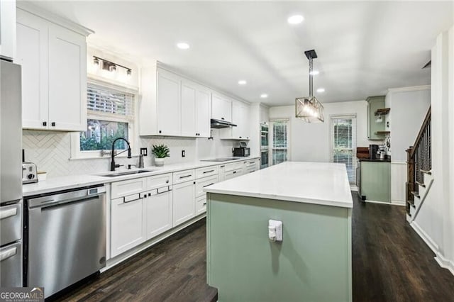 kitchen with white cabinetry, dark wood finished floors, a sink, light countertops, and dishwasher