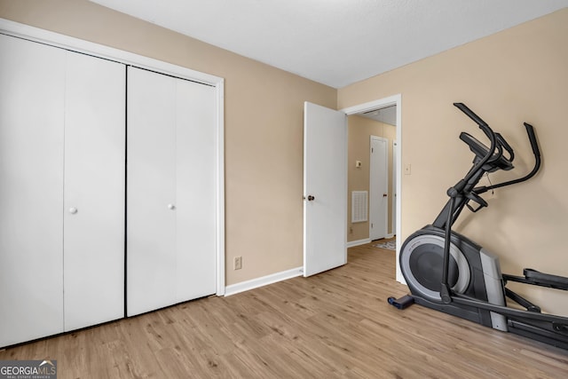 exercise room featuring visible vents, light wood-type flooring, and baseboards