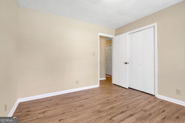 unfurnished bedroom featuring a closet, baseboards, and light wood finished floors