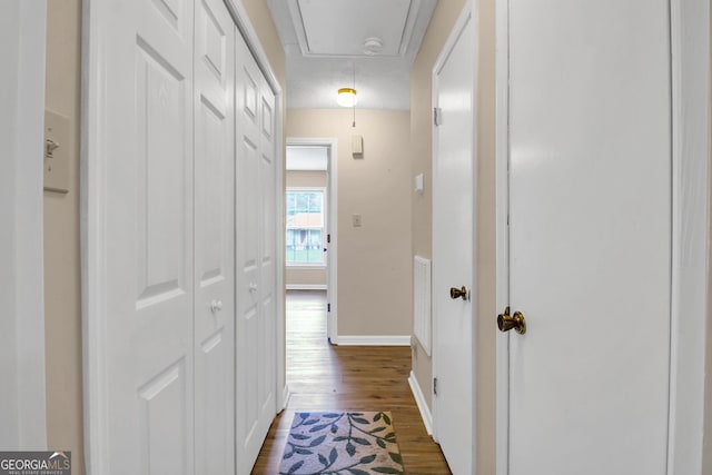 corridor with attic access, baseboards, and dark wood-style flooring