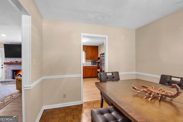 office area with parquet flooring, a fireplace, baseboards, and a textured ceiling