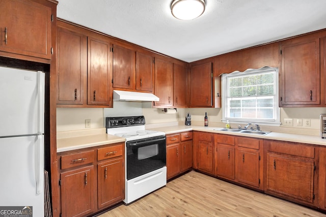 kitchen featuring white appliances, a sink, light countertops, light wood-style floors, and under cabinet range hood