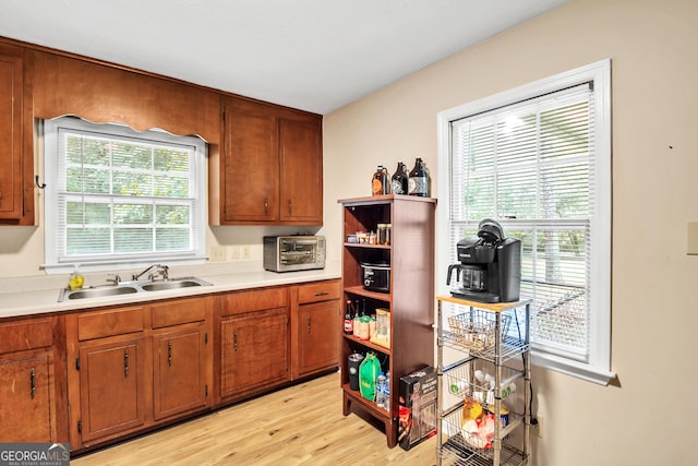 kitchen featuring light countertops, light wood-style floors, brown cabinets, and a sink