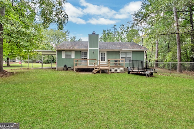 back of property featuring a wooden deck, a lawn, a fenced backyard, a carport, and a gate