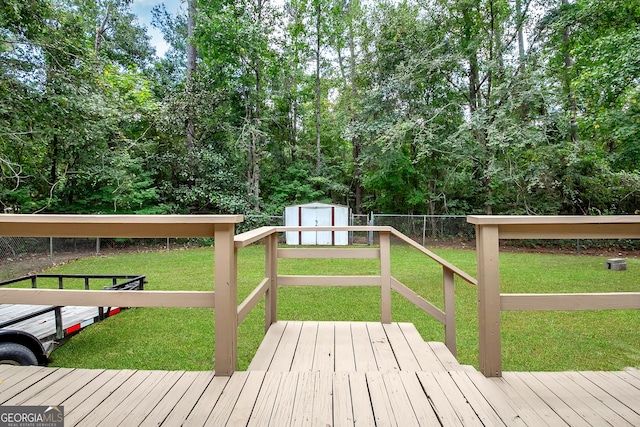 wooden terrace featuring a storage shed, a yard, an outbuilding, and fence