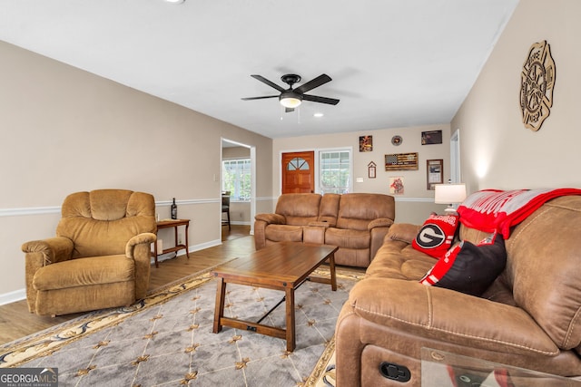 living area featuring wood finished floors, a ceiling fan, and baseboards