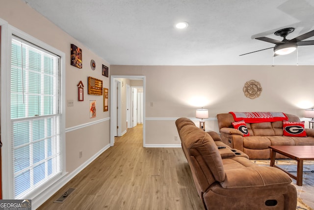 living room featuring visible vents, baseboards, light wood-style floors, and a ceiling fan