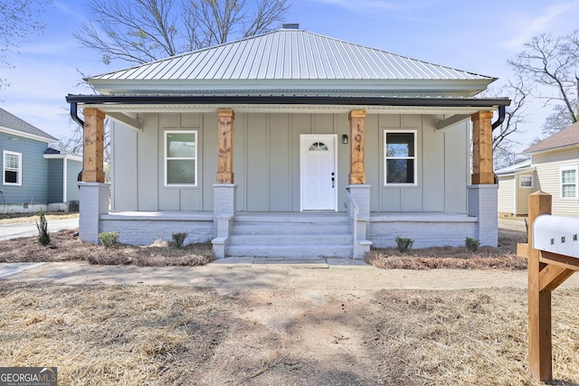 bungalow-style home with covered porch, board and batten siding, and metal roof