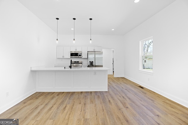 kitchen with visible vents, light countertops, a peninsula, stainless steel appliances, and white cabinetry