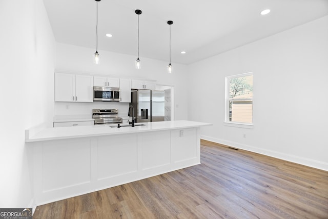 kitchen with white cabinetry, stainless steel appliances, light countertops, and a sink