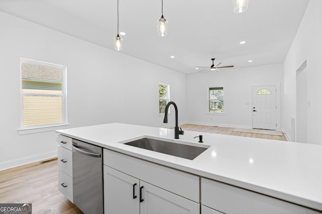 kitchen with decorative light fixtures, dishwasher, white cabinetry, and a sink