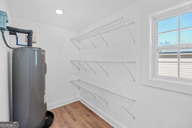 walk in closet featuring wood finished floors and water heater