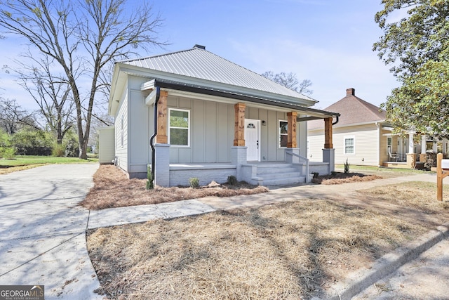 bungalow-style home featuring a porch, board and batten siding, concrete driveway, and metal roof