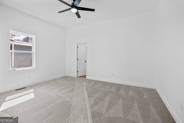 carpeted empty room with visible vents, baseboards, and ceiling fan