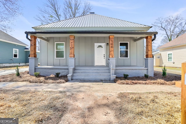 bungalow-style home with covered porch, board and batten siding, and metal roof