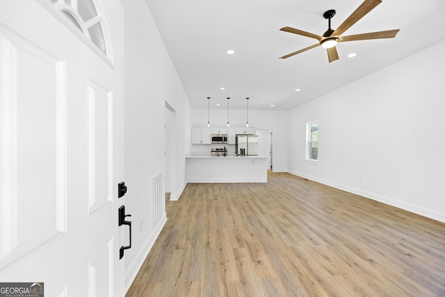 unfurnished living room with recessed lighting, light wood-type flooring, baseboards, and ceiling fan