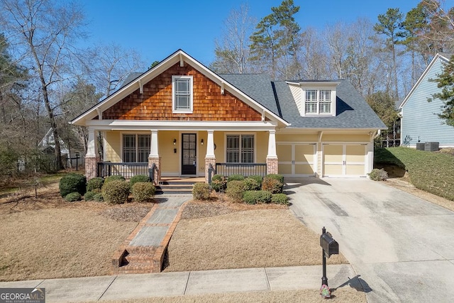 craftsman inspired home featuring a porch, a garage, driveway, and roof with shingles