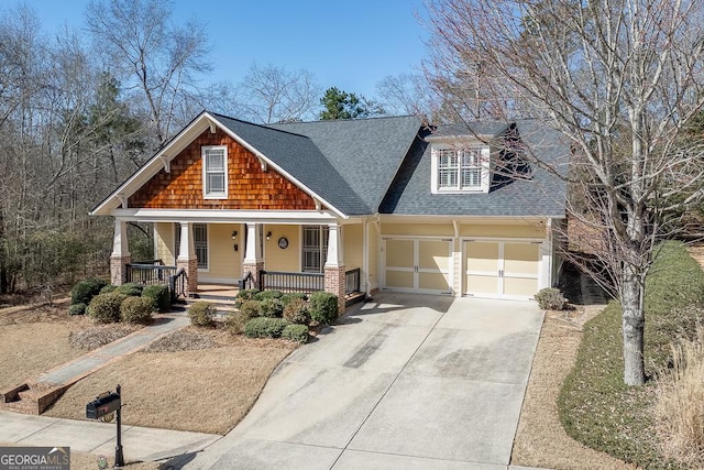 craftsman-style home featuring covered porch, an attached garage, concrete driveway, and a shingled roof