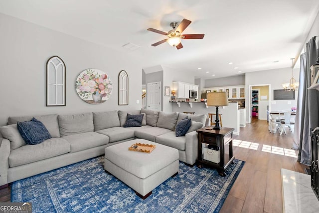 living area with ceiling fan with notable chandelier, recessed lighting, and wood finished floors