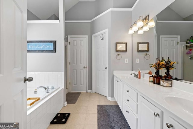 full bathroom featuring a garden tub, double vanity, lofted ceiling, tile patterned floors, and a sink