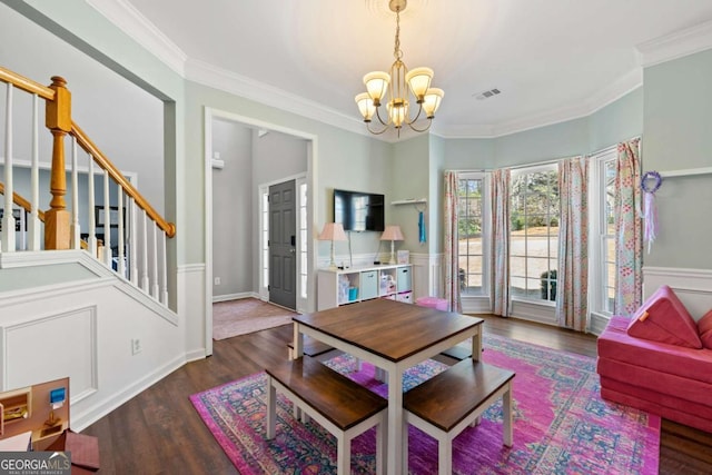 living room with visible vents, a notable chandelier, ornamental molding, wood finished floors, and stairway