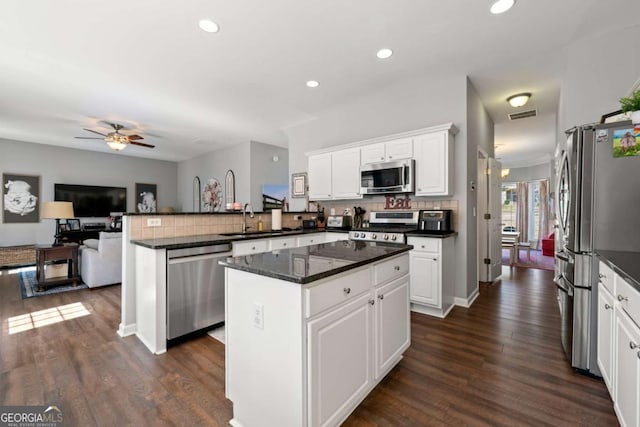 kitchen featuring a sink, open floor plan, appliances with stainless steel finishes, a peninsula, and ceiling fan