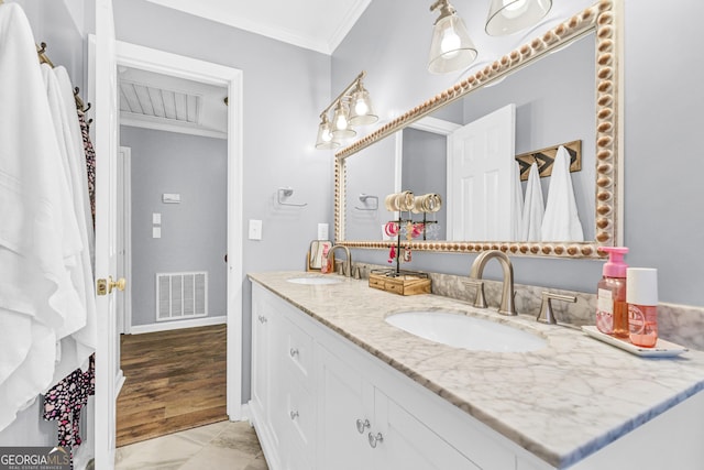 bathroom with a sink, visible vents, double vanity, and crown molding