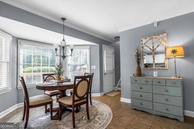 dining space with baseboards, dark tile patterned flooring, an inviting chandelier, and crown molding