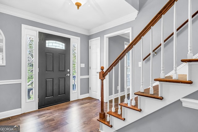 foyer featuring visible vents, hardwood / wood-style flooring, crown molding, baseboards, and stairs