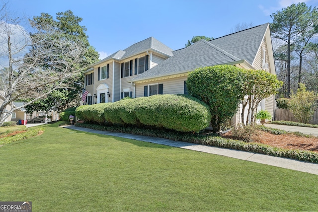 view of front facade with fence, concrete driveway, a front yard, a shingled roof, and a garage