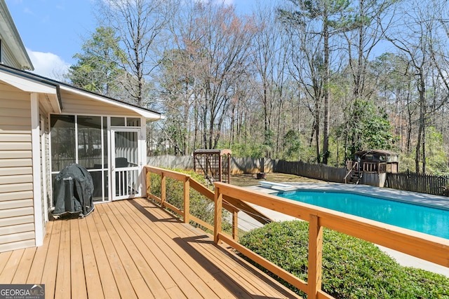 wooden terrace with a fenced backyard, a fenced in pool, and a sunroom