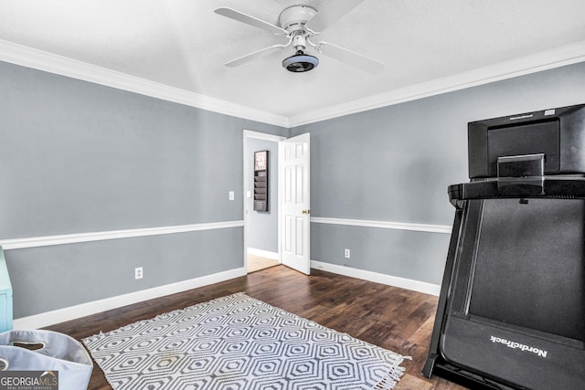 workout area with crown molding, wood finished floors, baseboards, and ceiling fan