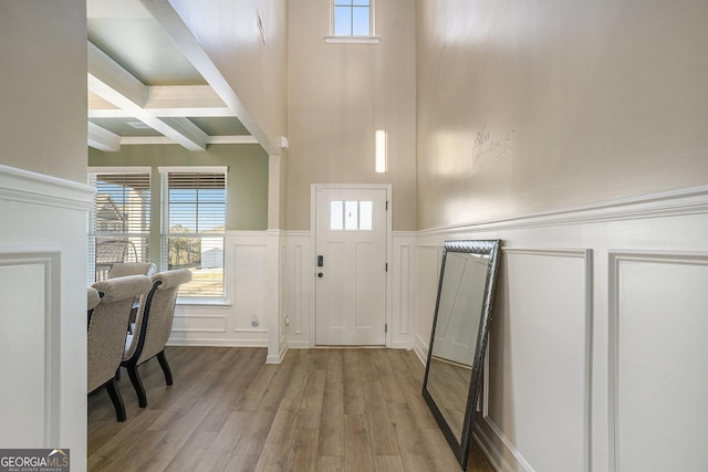 foyer with beamed ceiling, plenty of natural light, light wood-style floors, and coffered ceiling