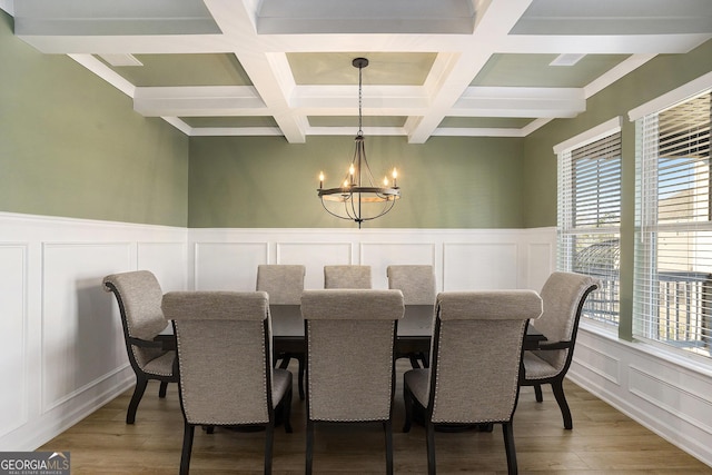 dining area with beam ceiling, light wood-type flooring, a wainscoted wall, and a chandelier