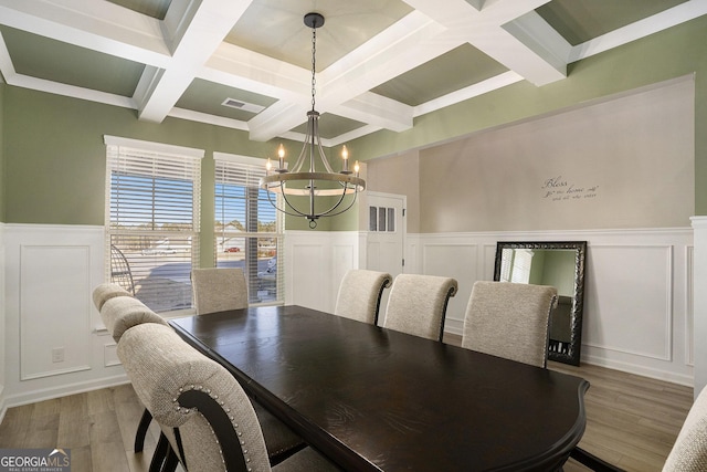 dining space featuring beamed ceiling, visible vents, light wood-style floors, an inviting chandelier, and a decorative wall