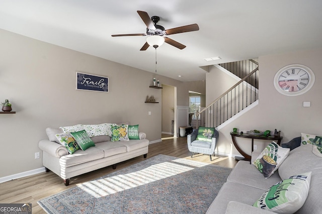 living area with ceiling fan, stairway, baseboards, and wood finished floors