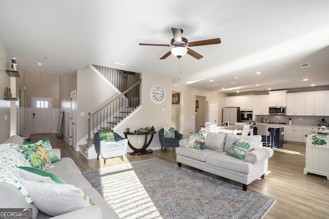 living area with light wood-style floors, visible vents, and ceiling fan