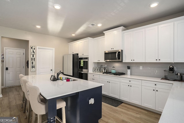 kitchen with a sink, a breakfast bar area, light wood finished floors, and stainless steel appliances