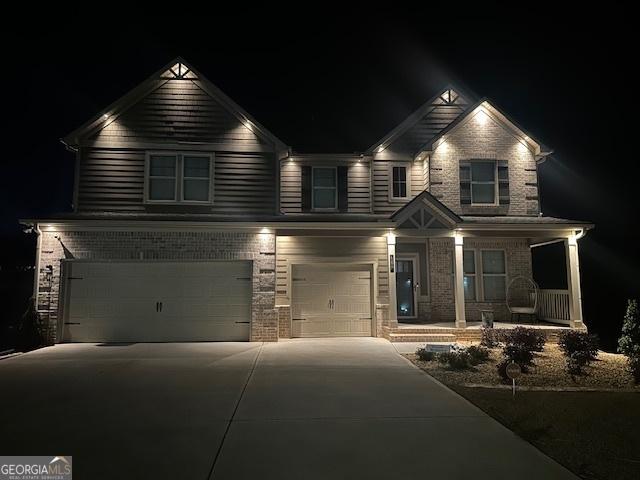 craftsman-style home with driveway, brick siding, covered porch, and an attached garage