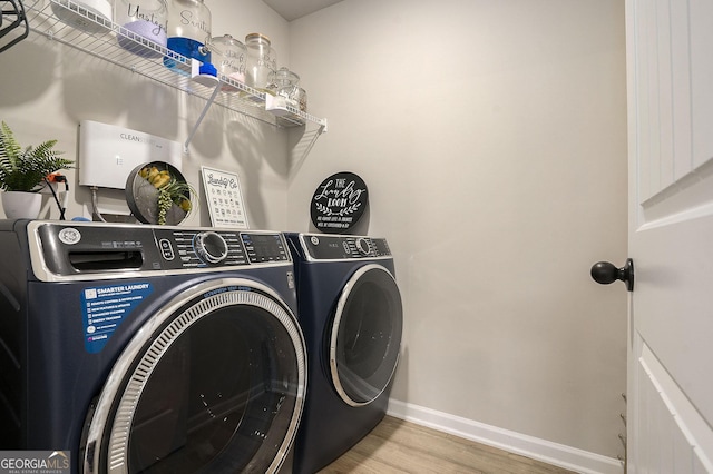 washroom featuring washer and dryer, baseboards, wood finished floors, and laundry area