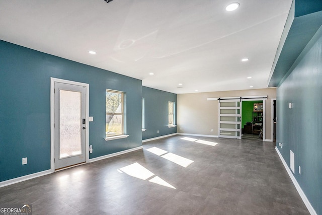 interior space with recessed lighting, baseboards, and a barn door