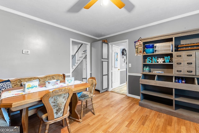 dining room with a ceiling fan, baseboards, light wood finished floors, stairs, and crown molding