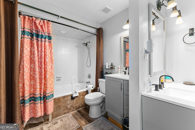 bathroom with vanity, wood finished floors, visible vents, toilet, and tiled shower / bath