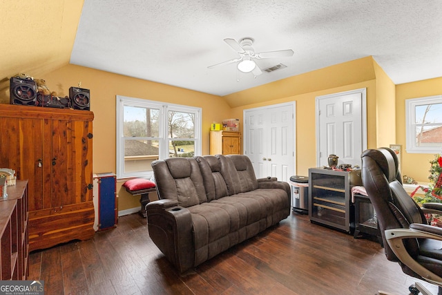 home office featuring beverage cooler, visible vents, ceiling fan, dark wood-type flooring, and vaulted ceiling