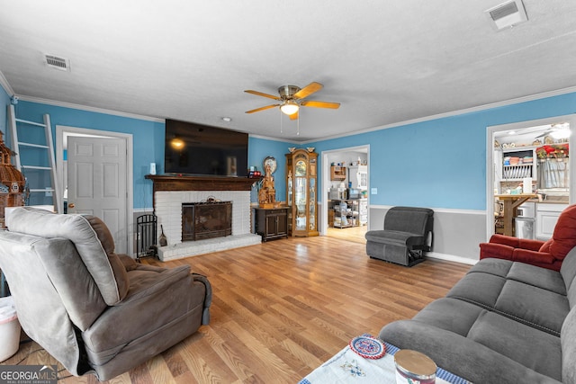 living area with visible vents, ornamental molding, a ceiling fan, and wood finished floors