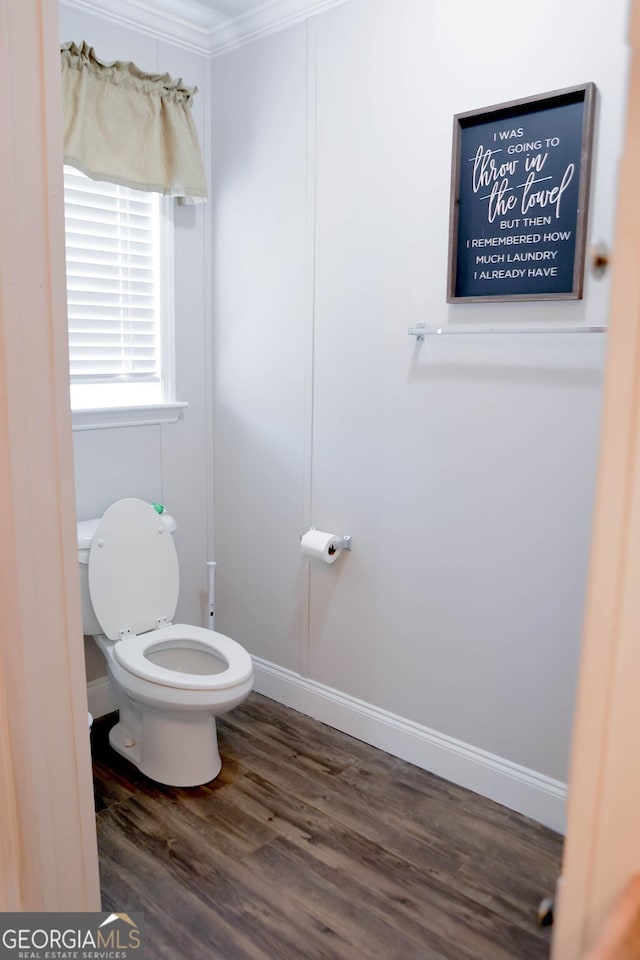 bathroom featuring toilet, crown molding, baseboards, and wood finished floors