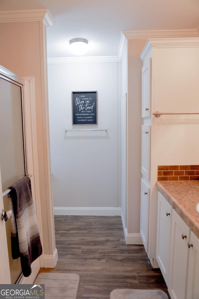 full bath with vanity, wood finished floors, baseboards, ornamental molding, and tasteful backsplash